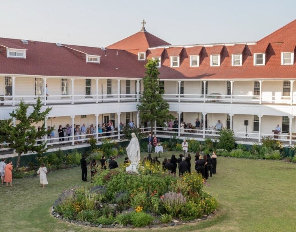 People stand in a courtyard surrounded by a building.