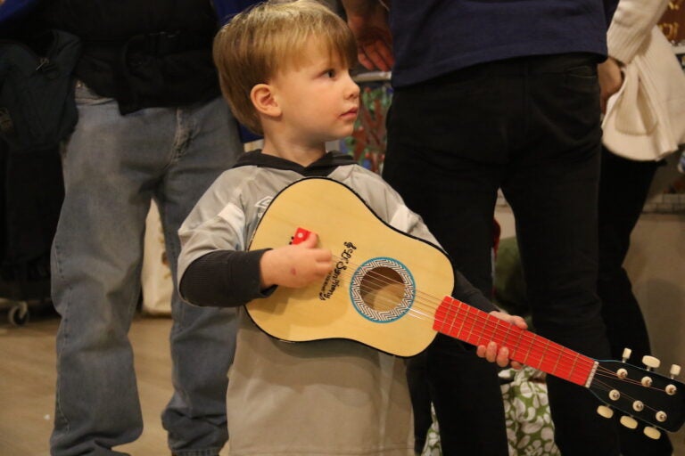 A little boy holds a small guitar.
