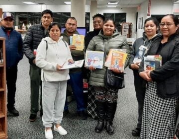 Parents pose with books in the library.