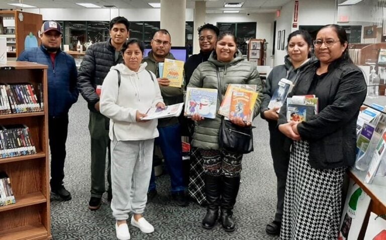 Parents pose with books in the library.