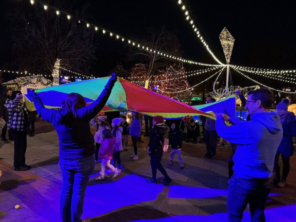 Kids and parents playing with a parachute.