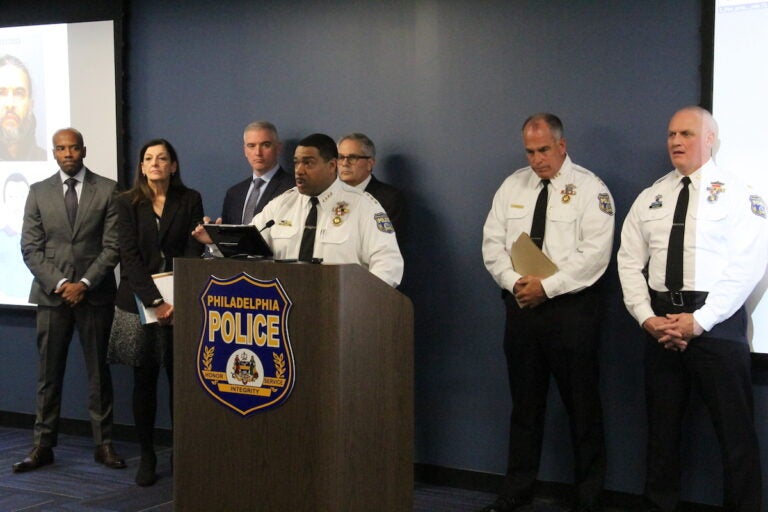 Philadelphia police and others stand at the front of a room during a press conference