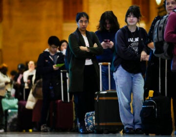 Travelers wait in line to board an Amtrak train in Philadelphia