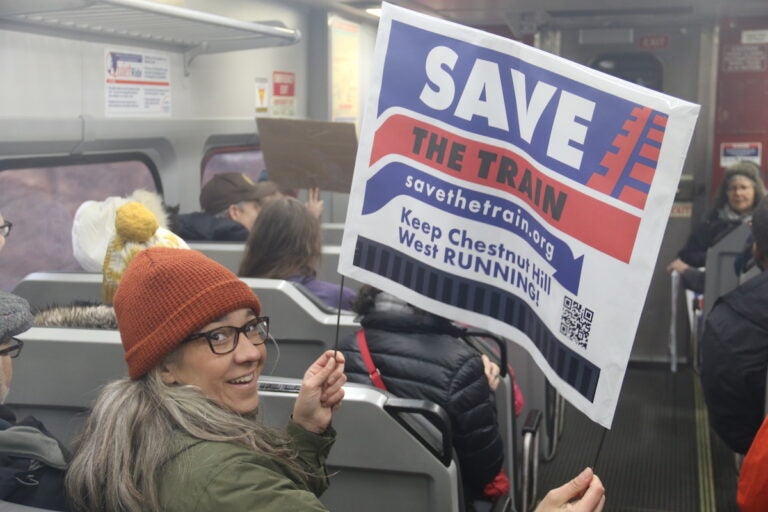 While onboard, ''Save The Train'' supporters flashed their signs advocating for the Chestnut Hill West line to maintain service in case cuts are made across SEPTA. (Cory Sharber/WHYY)