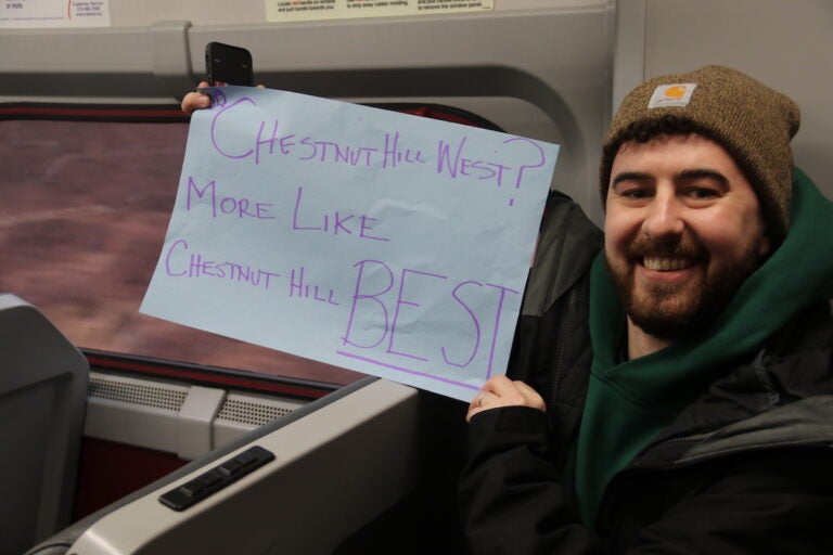 While onboard, ''Save The Train'' supporters flashed their signs advocating for the Chestnut Hill West line to maintain service in case cuts are made across SEPTA. (Cory Sharber/WHYY)