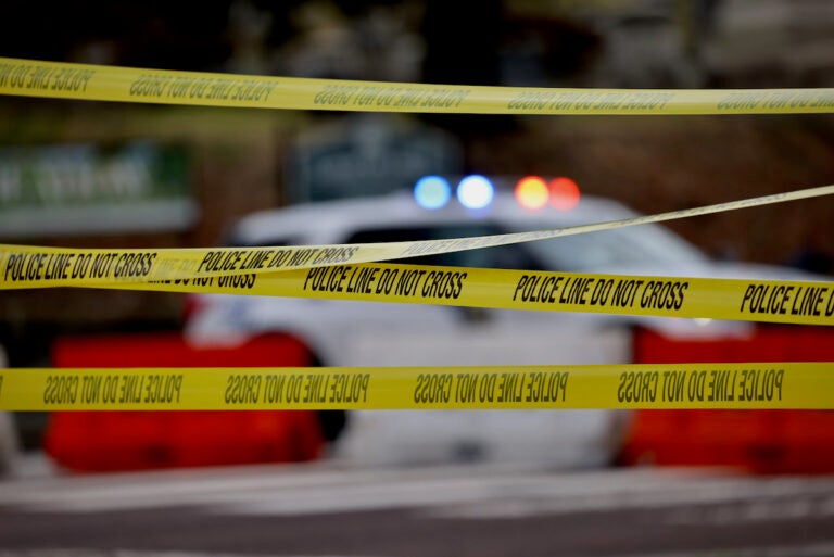 Police tape and the flashing lights of a police vehicle behind