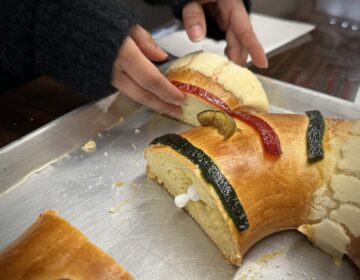 A rosca de reyes is sliced to reveal the baby Jesus figurine inside at Amigos Bakery on 9th street. (Ali Mohsen/Billy Penn)