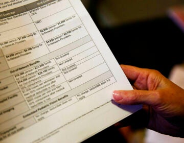 A close-up of a health insurance coverage form being held by someone.