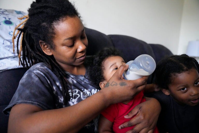 Ashley Yancey feeds her 11 month-old daughter Olivia as two-year old Oliver Tolvert looks on at right