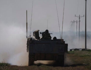 Israeli soldiers travel on an army armored personnel carrier (APC) near the Israeli-Gaza border as smoke rises to the sky in the Gaza Strip, seen from southern Israel, Sunday, Jan. 21, 2024. (AP Photo/Leo Correa)