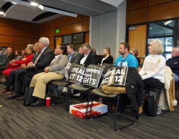 Local water officials and residents alike filled the conference room in West Whiteland and placed signs in the first few seats calling for an appeal of Act 12. (Kenny Cooper/WHYY)
