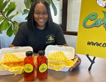 Nija Wiggins poses, smiling, with some of her corn on the cob specialties in front of her.