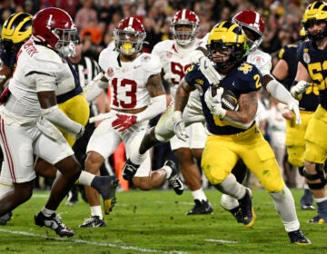 Michigan running back Blake Corum (2) runs in for a touchdown past Alabama defensive back Kool-Aid McKinstry (1) during overtime at the Rose Bowl CFP NCAA semifinal college football game Monday, Jan. 1, 2024, in Pasadena, Calif. (AP Photo/Kyusung Gong)