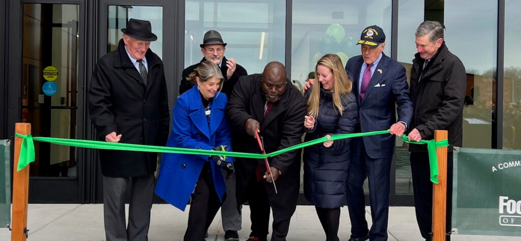 People cut a ribbon outside of a building.