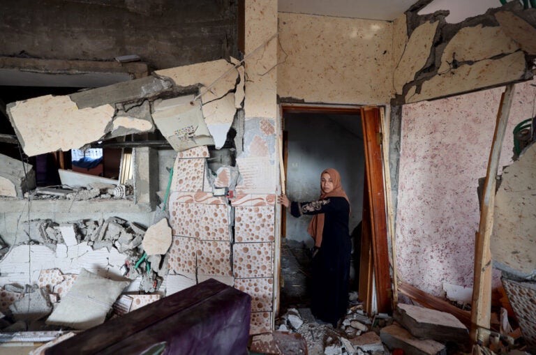 A woman stands in her damaged house in Rafah