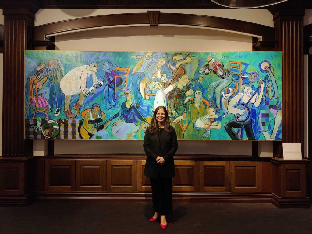 National Liberty Museum chief program officer Elizabeth Grant stands in front of Joyce Garner’s monumental painting “Musical Chairs”