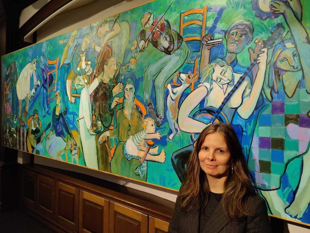 National Liberty Museum chief program officer Elizabeth Grant stands in front of Joyce Garner’s monumental painting “Musical Chairs”
