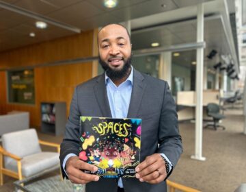 Omari Baye holds a book he authored called “Spaces”