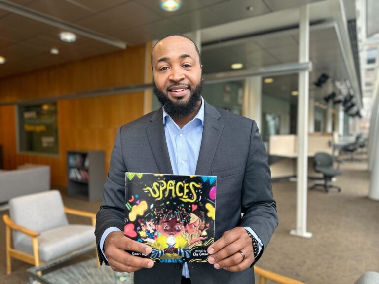 Omari Baye holds a book he authored called “Spaces”