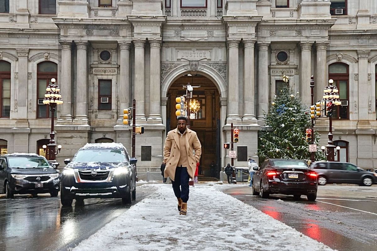 A person walking in the snow in the street in front of City Hall in Philadelphia