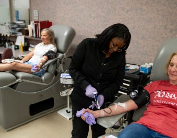 A medical professional helps a woman who is donating blood.