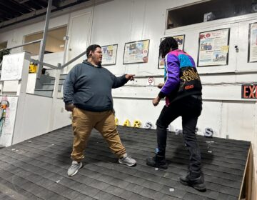 Trainer Moises Morales (left) and Eric Coleman (right) on a model rooftop. (Sophia Schmidt/WHYY)