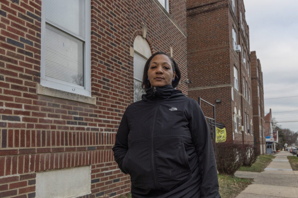 Juanita Clark poses for a photo outside of Oak Lane Court apartments