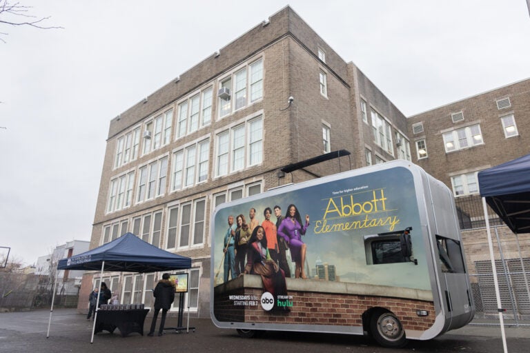 A truck with an advertisement for Abbott Elementary is parked outside of a school building.