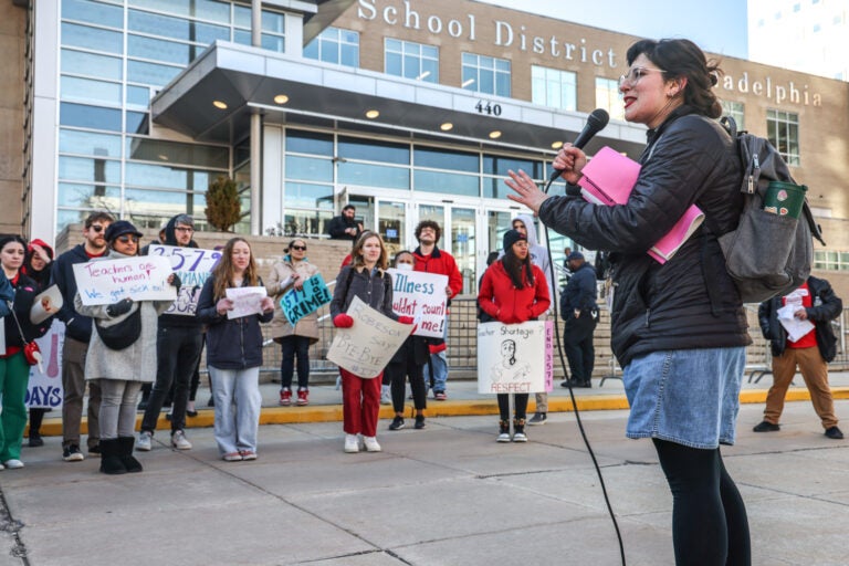 Jessie Shapiro speaks into a microphone in front of protesters at the School District of Philadelphia