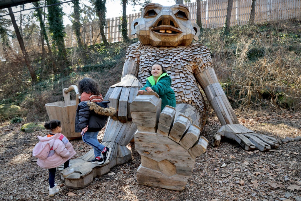 Children clamber on thee feet of the troll sculpture Basse Buller