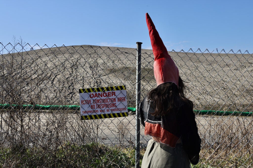 Alex Tatarsky stands before a mound of dirt that covers what was once a meadow.