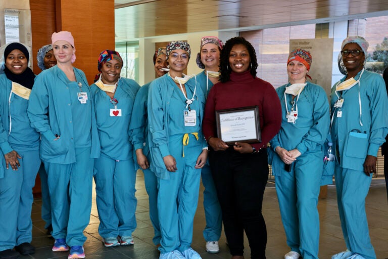 Shariah Harris is surrounded by her colleagues as she holds her certificate of recognition from Lankenau Medical Center, where she is an operating room nurse.