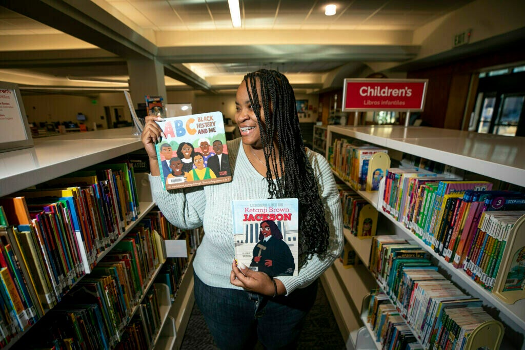 Blair-Caldwell African American Research Library senior librarian Jameka Lewis holds some of her favorite books. Jan. 16, 2024.