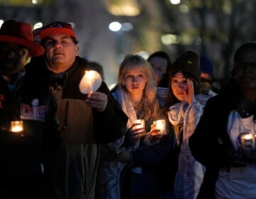 People hold candles at a vigil