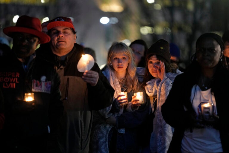 People hold candles at a vigil