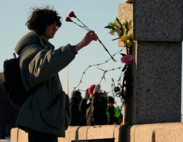 A woman places flowers as people pay tribute to Alexei Navalny at the Memorial to Victims of Political Repression in St. Petersburg, Russia, Sunday, Feb. 18, 2024. Russians across the vast country streamed to ad-hoc memorials with flowers and candles to pay tribute to Alexei Navalny, the most famous Russian opposition leader and the Kremlin's fiercest critic. Russian officials reported that Navalny, 47, died in prison on Friday.