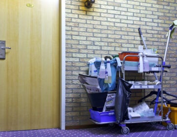 A cleaning cart beside the door of a hotelroom.
