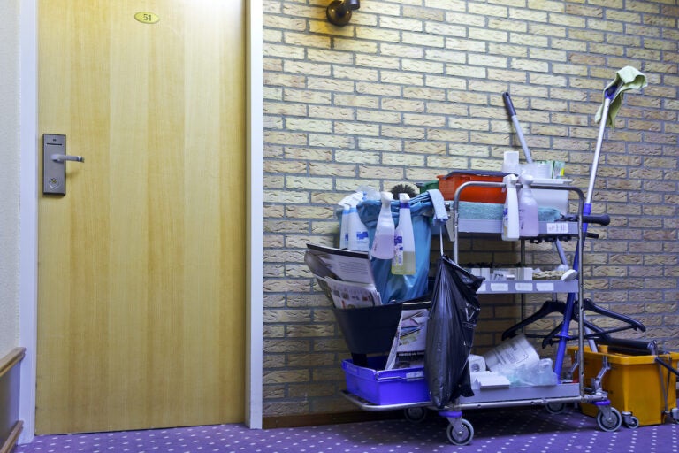 A cleaning cart beside the door of a hotelroom.