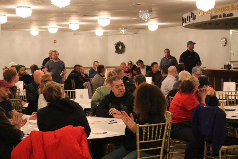 A room full of people seated at round tables at the Mummers Museum