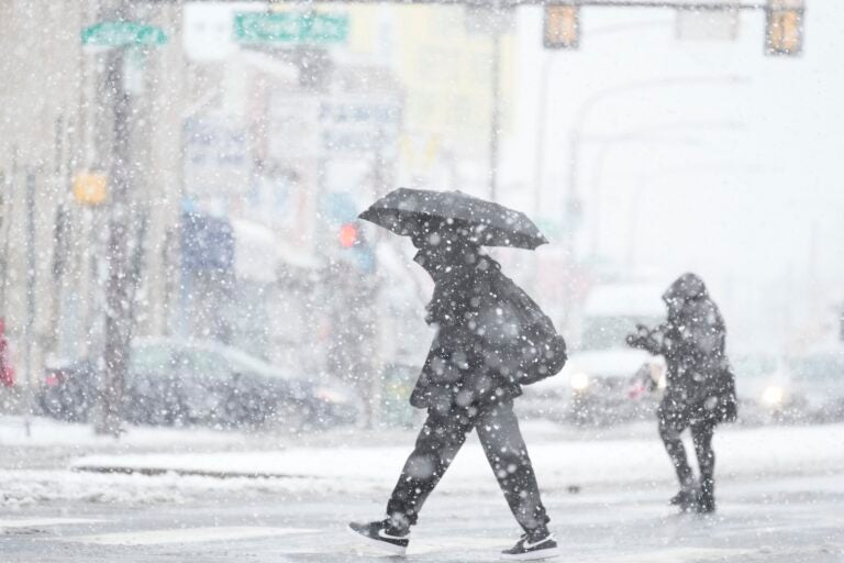 People cross a street during a winter snow storm in Philadelphia, Tuesday, Feb. 13, 2024.