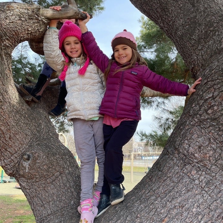 Two kids pose for a photo in a tree