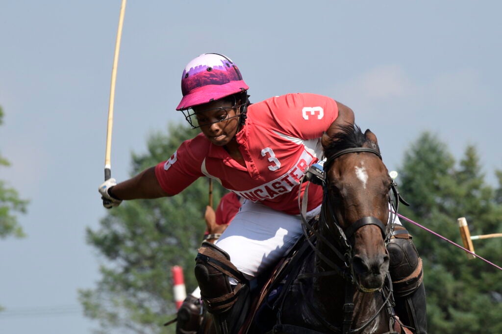 Shariah Harris rides a horse while playing polo