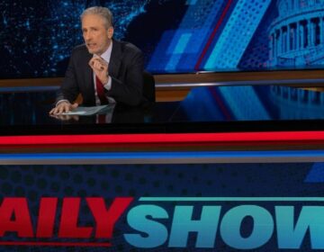 Jon Stewart sits at the Daily Show desk on his the first night of his return.