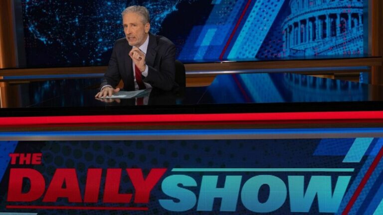 Jon Stewart sits at the Daily Show desk on his the first night of his return.