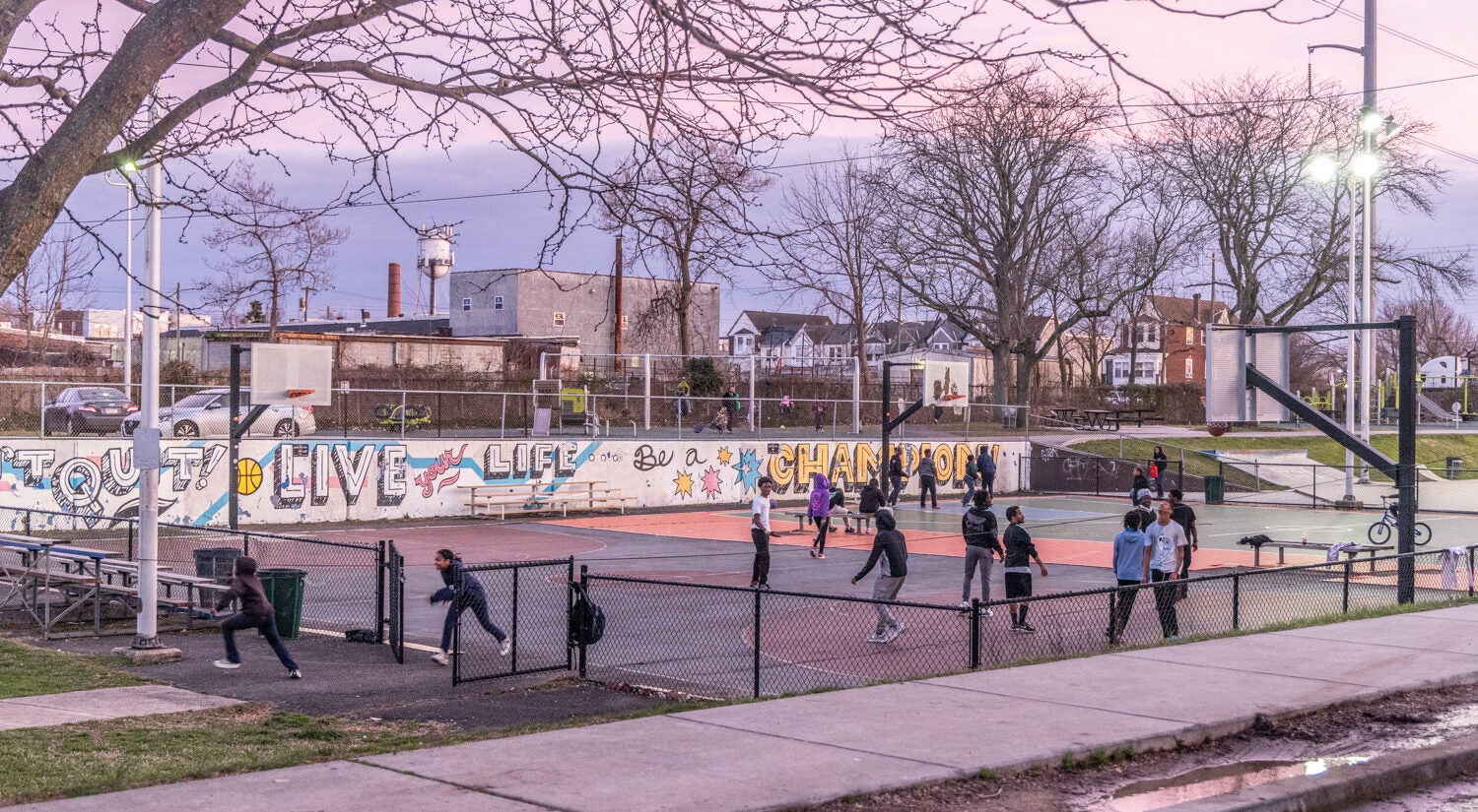 Kids playing on a basketball court at twilight