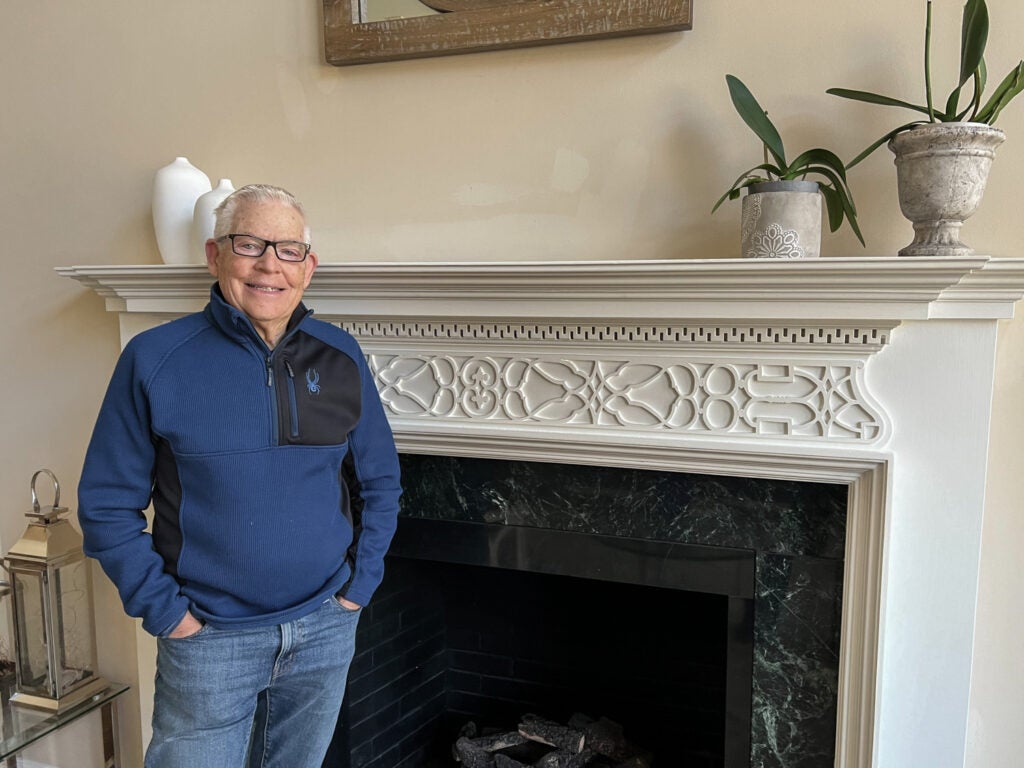 Bob Hurka poses for a photo in his house beside his fireplace