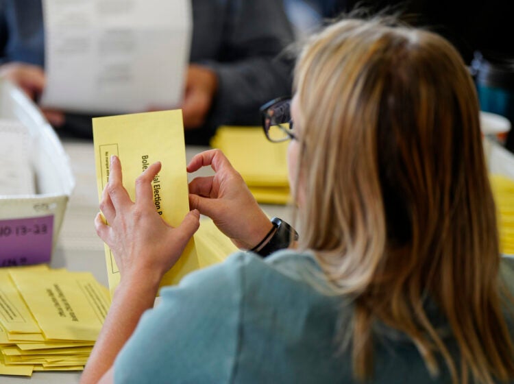 An election worker is sorting mail-in ballots
