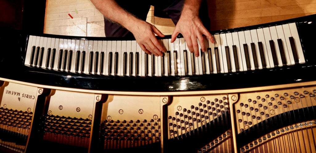 A view from above of a musician playing an ergonomically-curved grand piano