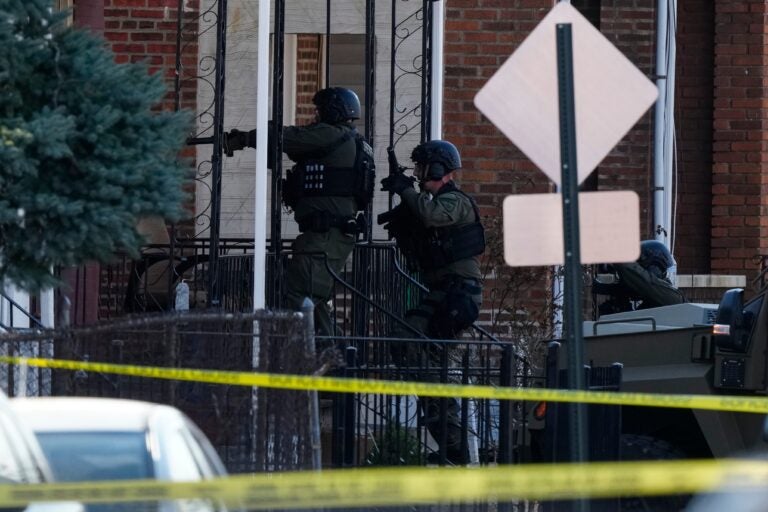 Law enforcement officers enter an empty apartment home in Trenton, N.J.