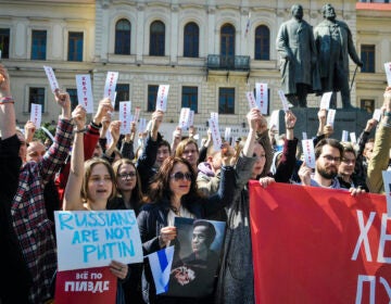 People hold sheets reading ''enough'' as they protest in downtown Tbilisi, Georgia, Sunday, March 17, 2024. Russians at home and abroad are heading to the polls for a presidential election that is all but certain to extend President Vladimir Putin's rule after he clamped down on dissent.